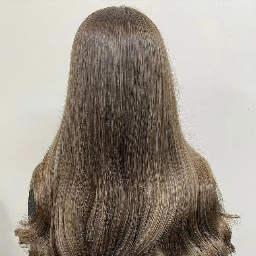 Long natural brown hair with subtle highlights and a soft curl