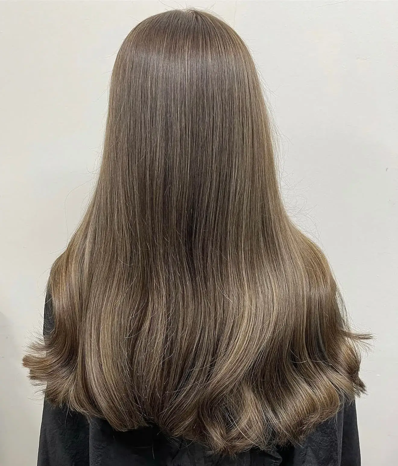 Long natural brown hair with subtle highlights and a soft curl