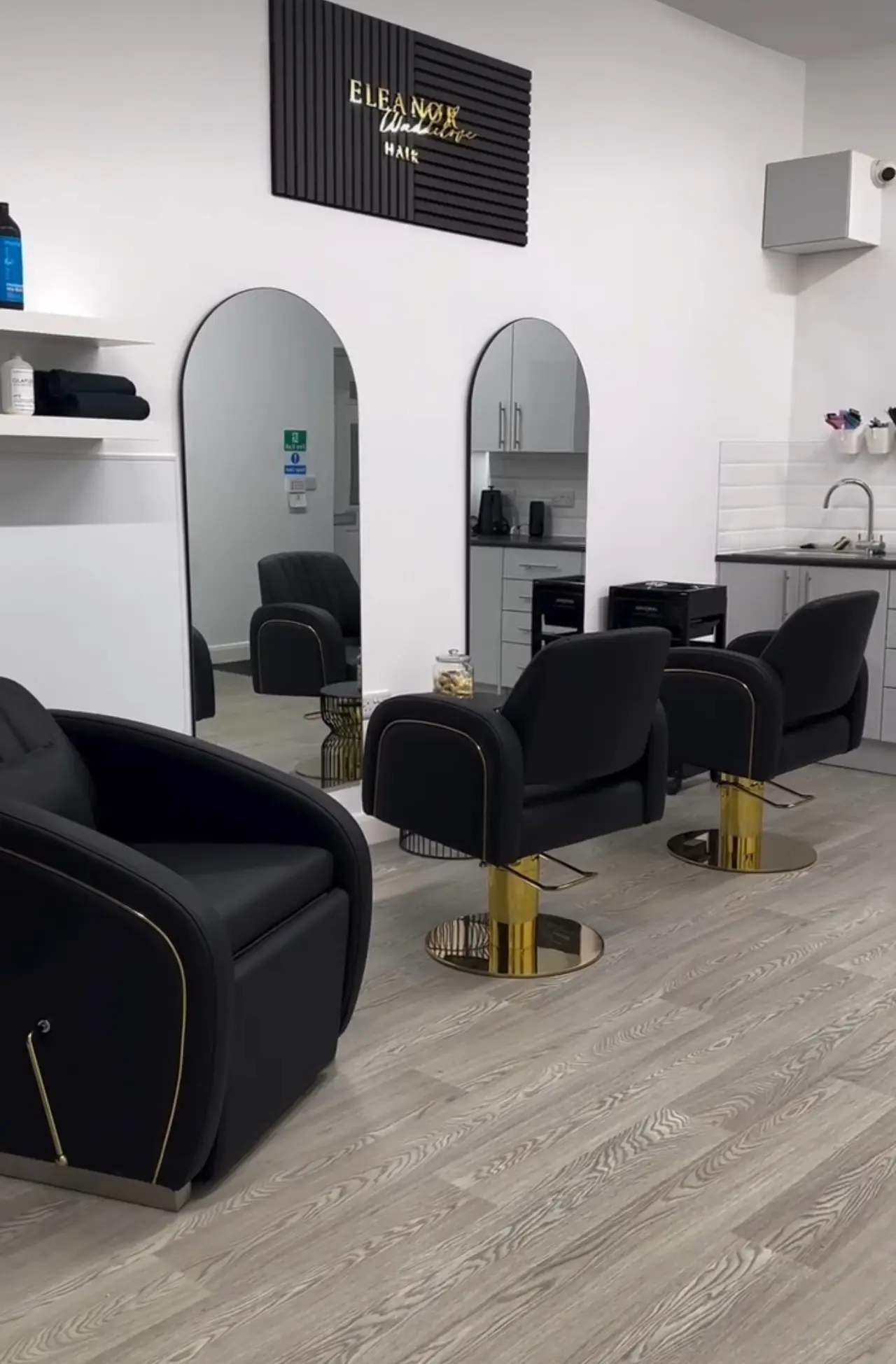 Inside Eleanor Waddilove Hair: black and gold styling chairs beneath the salon's branded sign, in Oswaldtwistle, Lancashire